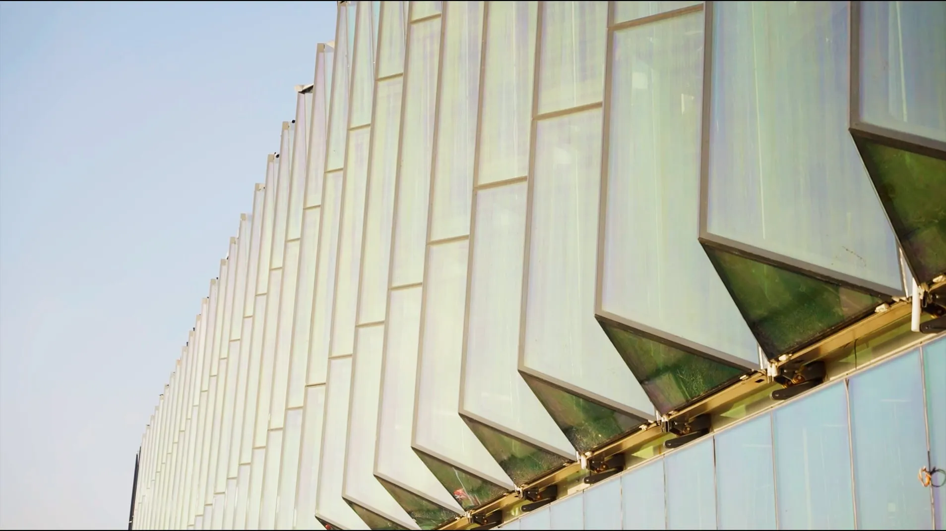 Close view of the angled glass panels of the terminal facade against the sky.